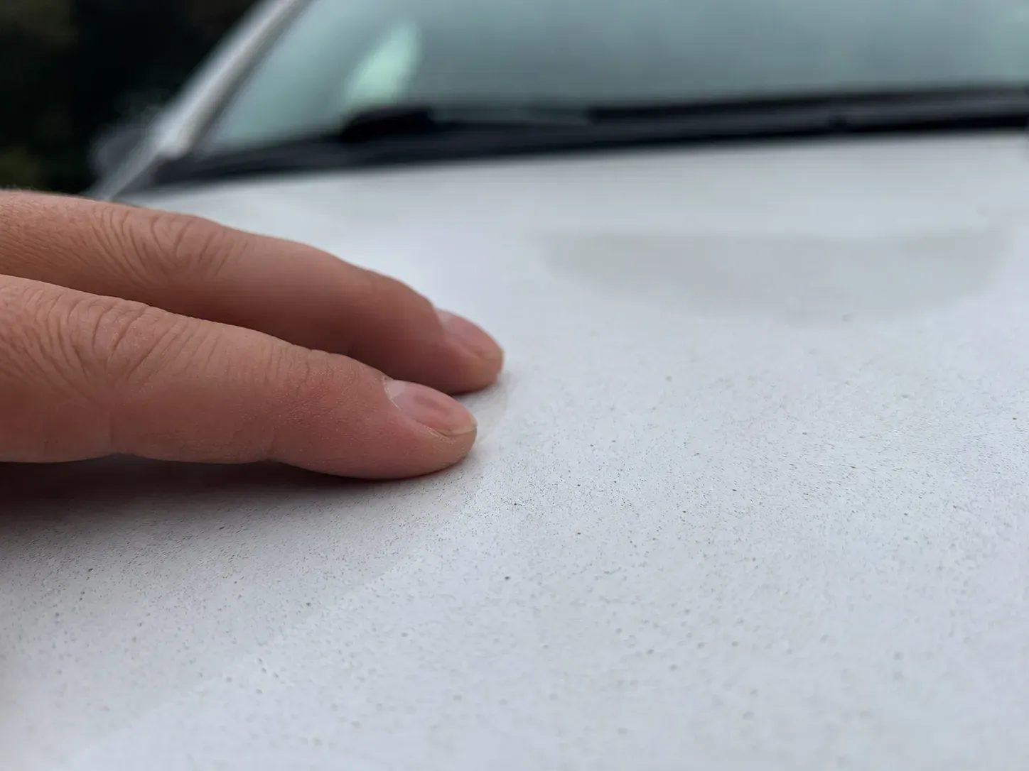 Close-up feeling bonded paint contamination before clay bar treatment