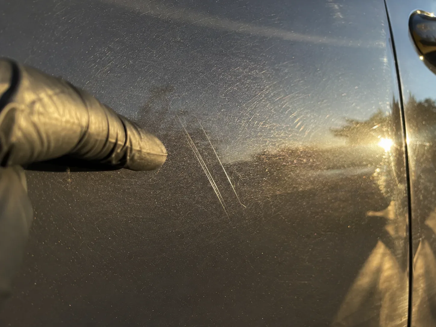Detailer inspecting deep paint scratches beyond clay bar treatment scope