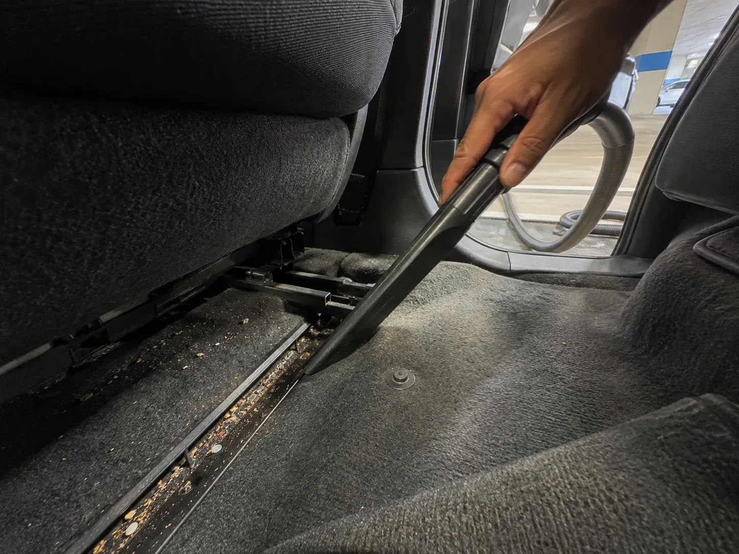 Vacuuming under the seats of a car in Irving