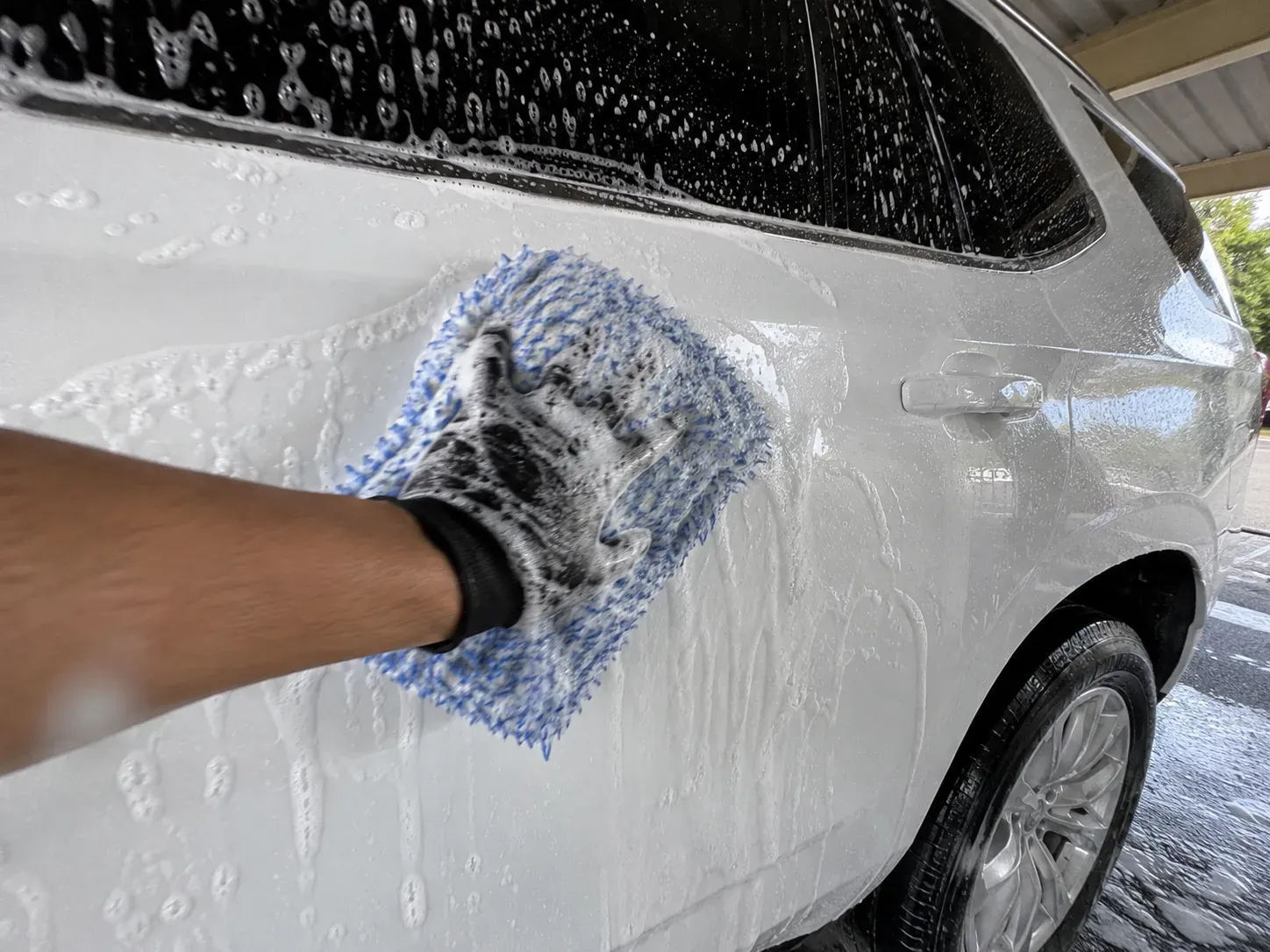 Hand washing a car exterior with a wash mitt in Irving