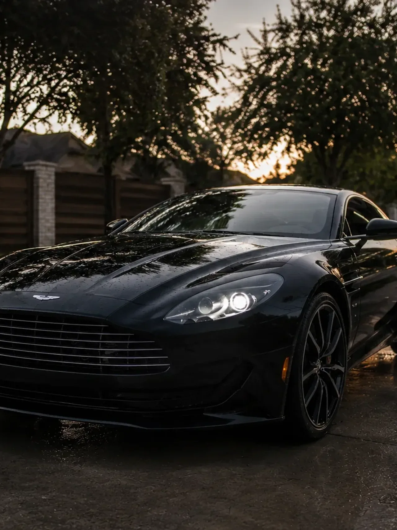 Freshly detailed black sports car on a wet Irving street at dusk