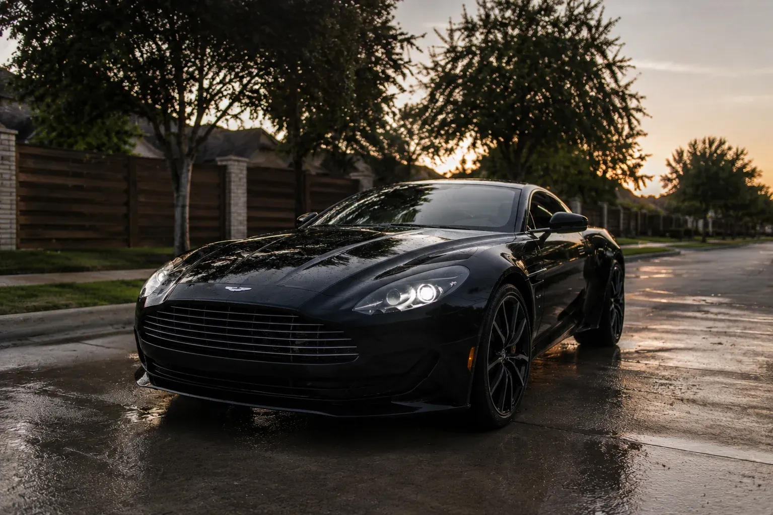 Freshly detailed black sports car on a wet Irving street at dusk