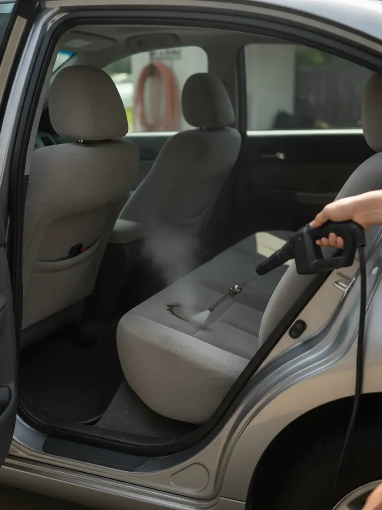 Technician steam cleaning car seat fabric during mobile detailing in Fort Worth